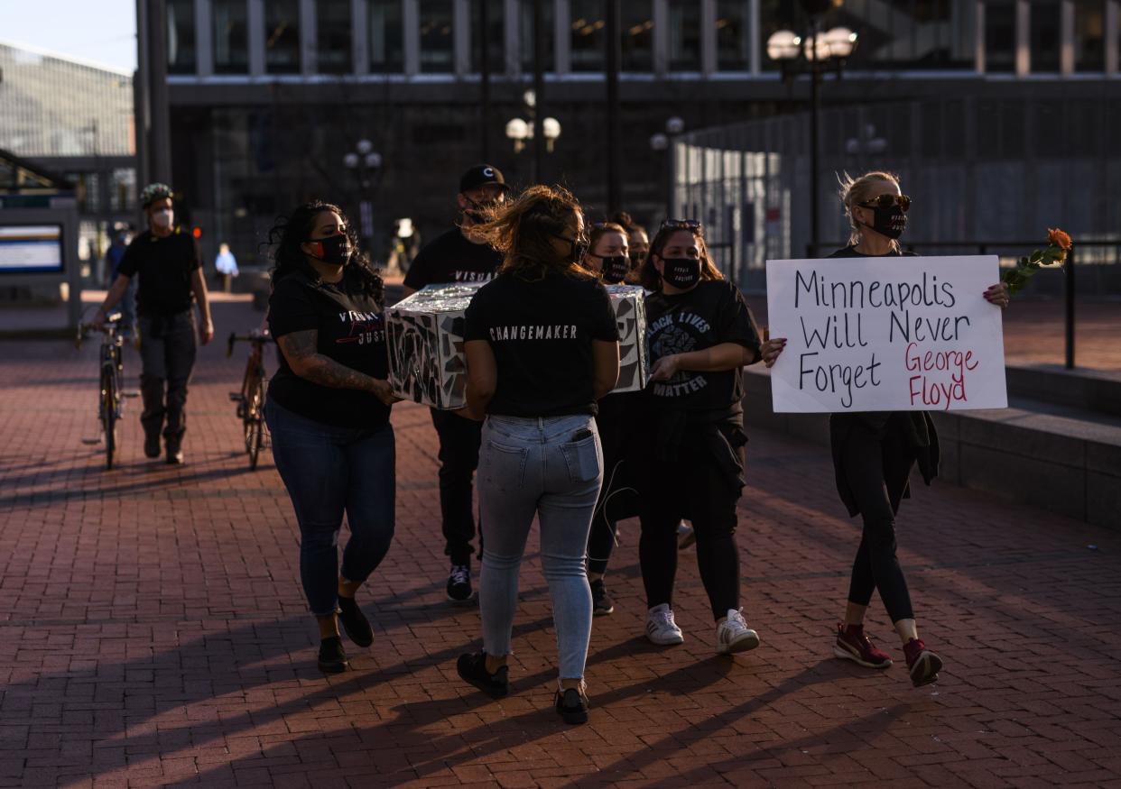 Demonstrators carry a coffin decorated with mirrors outside the Hennepin County Government Center on March 29, 2021, in Minneapolis, Minnesota.