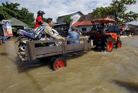 Residents sit on a loader as it makes its way down a flooded street at Srimahaphot district in Prachin Buri province, east of Bangkok September 24, 2013. REUTERS/Chaiwat Subprasom