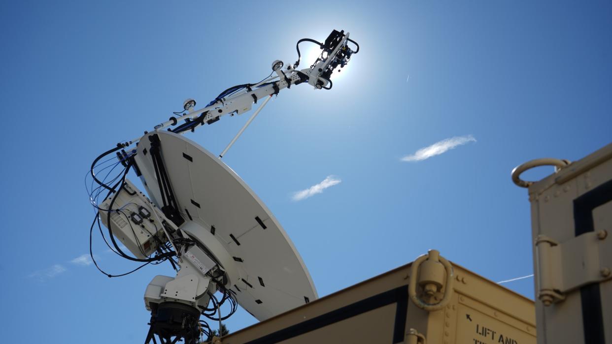  A white satellite dish points upward into a clear sky. 