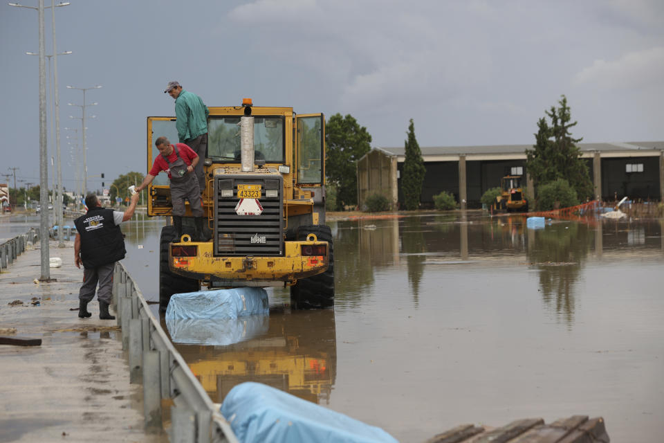 Workers stand on a bulldozer in a flooded area after a rainstorm, in Larissa, Thessaly region, central Greece, Thursday, Sept. 7, 2023. Greece's fire department says more than 800 people have been rescued over the past two days from floodwaters, after severe rainstorms turned streets into raging torrents, hurling cars into the sea and washing away roads. (AP Photo/Vaggelis Kousioras)