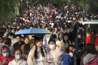 Visitors wearing face masks to protect against COVID-19 walk across a causeway at the West Lake in Hangzhou in eastern China's Zhejiang Province, Sunday, April 4, 2021. Domestic tourists were out in force at some of China's most popular tourist sites on a holiday weekend as the country continues to report few new cases of coronavirus within its borders. (AP Photo/Mark Schiefelbein)