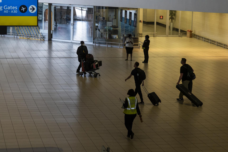 Passengers make their way through Johannesburg's OR Tambo's airport Monday Nov. 29, 2021. The World Health Organisation urged countries around the world not to impose flight bans on southern African nations due to concern over the new omicron variant. (AP Photo/Jerome Delay)