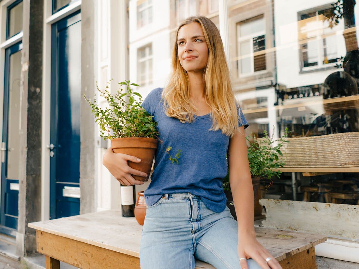 Netherlands, Maastricht, blond young woman holding flowerpot in the city