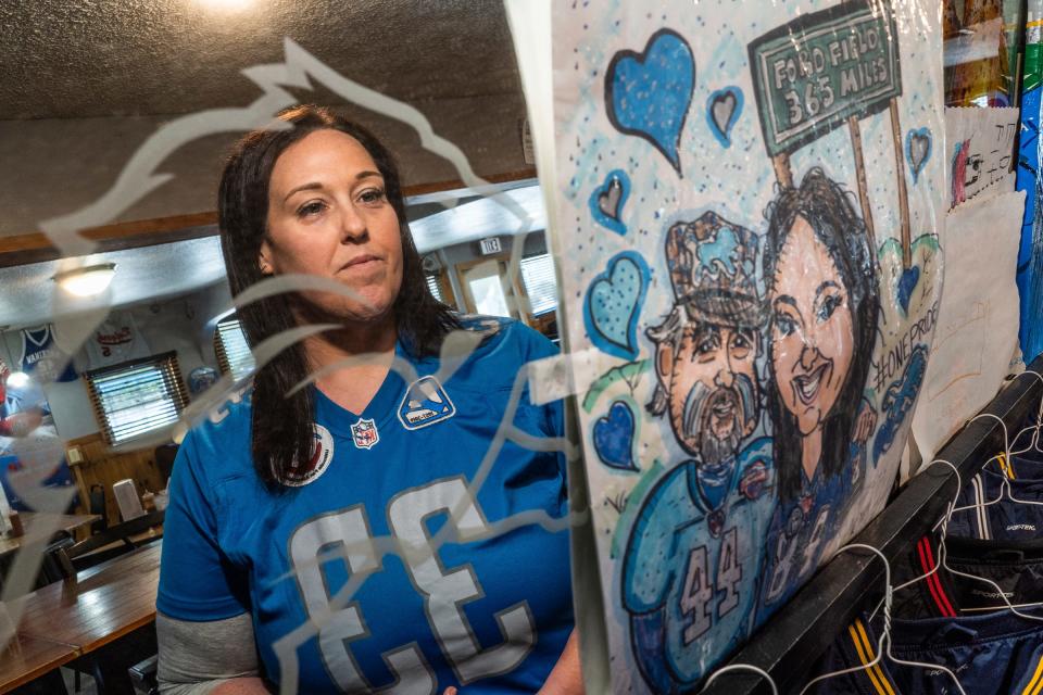 Detroit Lions superfan Megan "Yoopergirl" Stefanski stands near a drawing of her and her father, Detroit Lions superfan Donnie "Yooperman" Stefanski, at her family's restaurant named Yooperman's Bar & Grill in Goetzville on Wednesday, Aug. 30, 2023.