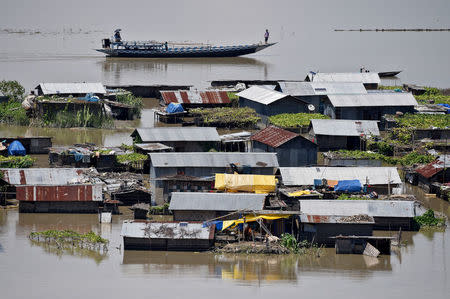 Villagers use a boat as they row past partially submerged houses at a flood-affected village in Morigaon district in Assam, July 14, 2017. REUTERS/Anuwar Hazarika