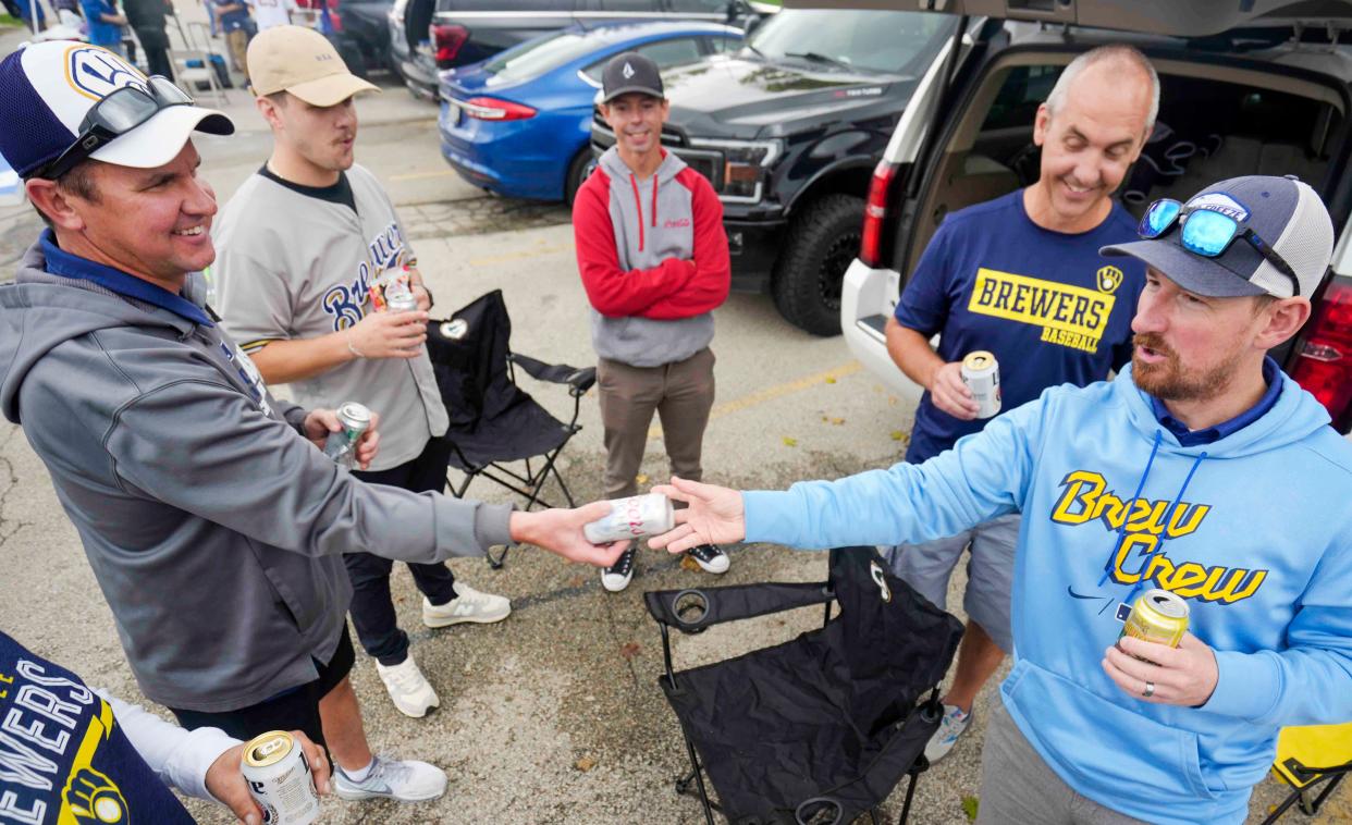 Tim Itzen, left, receives a Coors Light beer from Jason Strong as they tailgate Thursday, Sept. 28, 2023, at American Family Field in Milwaukee.