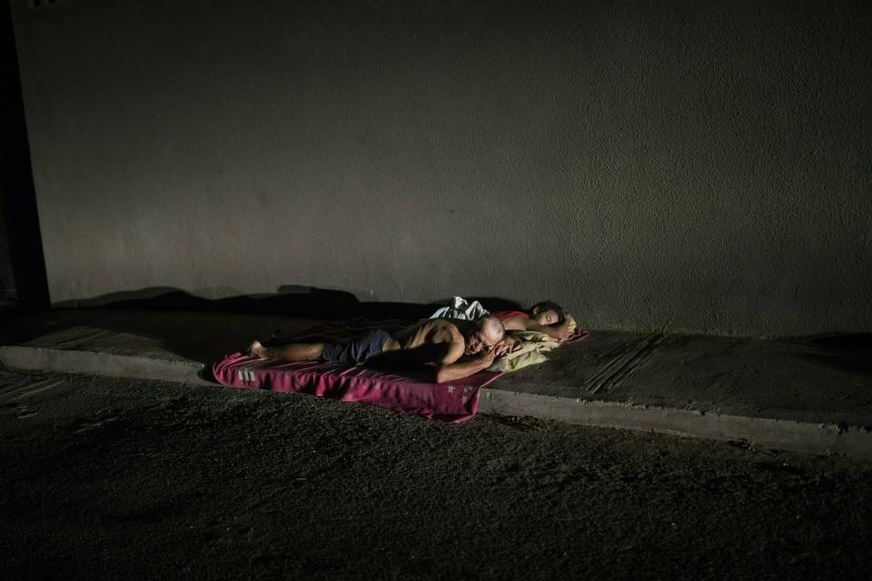 In this May 15, 2019 photo, people sleep on the sidewalk to escape from the heat, due to the lack of electricity in their homes that does not allow them to run their air conditioners and fans, during a blackout in Maracaibo, Venezuela. Maracaibo's sweltering heat approaches 100 degrees (37 centigrade) most days, making the air conditioner a must. (AP Photo/Rodrigo Abd)