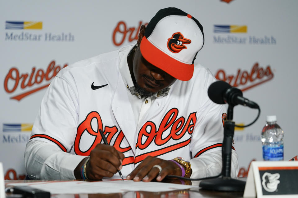 Former Baltimore Orioles player Adam Jones signs a contract to officially retire prior to a baseball game between the Orioles and the Tampa Bay Rays, Friday, Sept. 15, 2023, in Baltimore. (AP Photo/Julio Cortez)