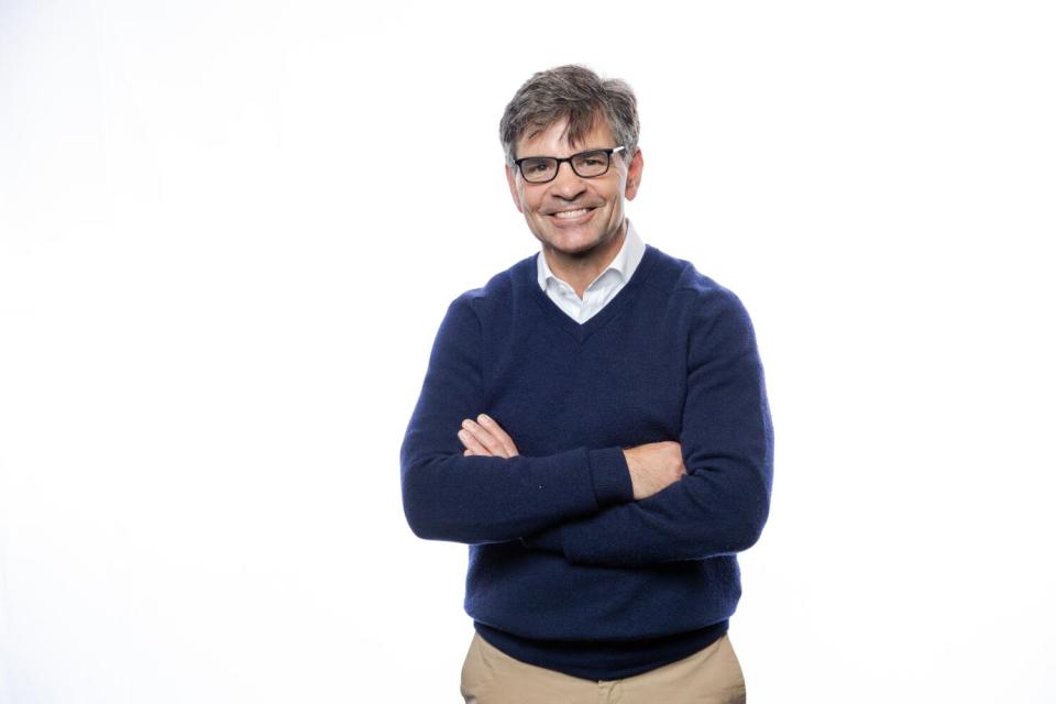 A smiling man stands with his arms crossed.