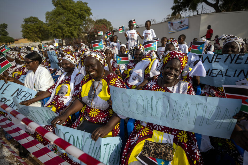 Women holding national flags and peace banners await the arrival of Pope Francis at the St. Theresa Cathedral in Juba, South Sudan Saturday, Feb. 4, 2023. Pope Francis is in South Sudan on the second leg of a six-day trip that started in Congo, hoping to bring comfort and encouragement to two countries that have been riven by poverty, conflicts and what he calls a "colonialist mentality" that has exploited Africa for centuries. (AP Photo/Ben Curtis)