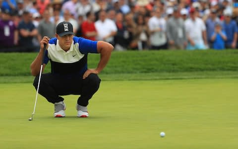 Brooks Koepka gets down to line up his putt on the 1st group - Credit: Getty Images North America