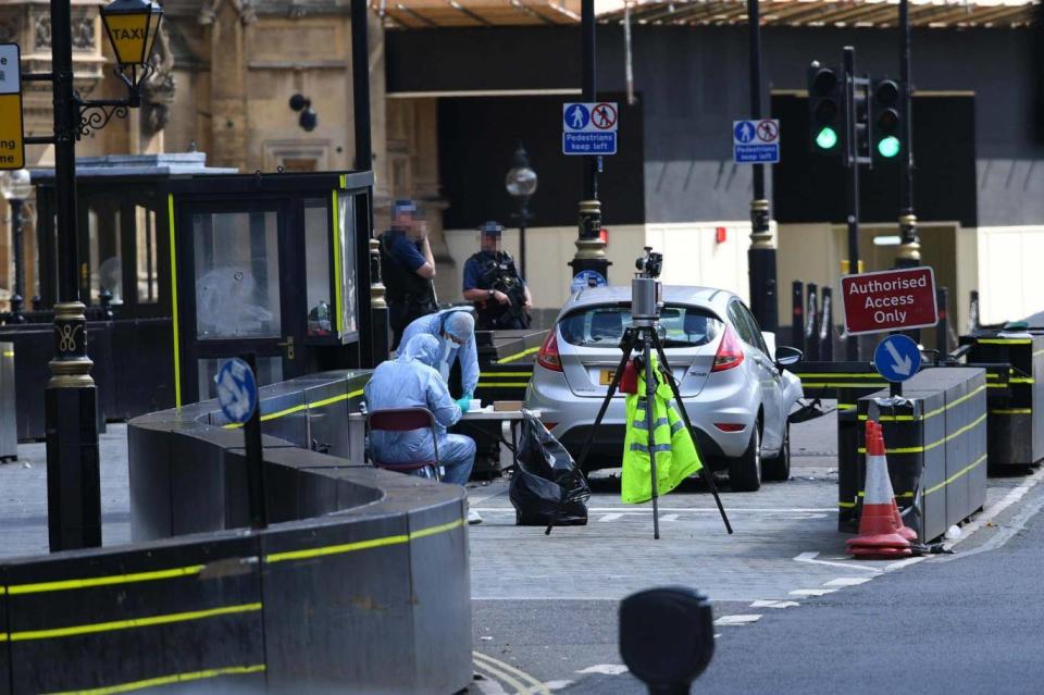 Forensic officers examine the car that crashed into the security barriers (PA)