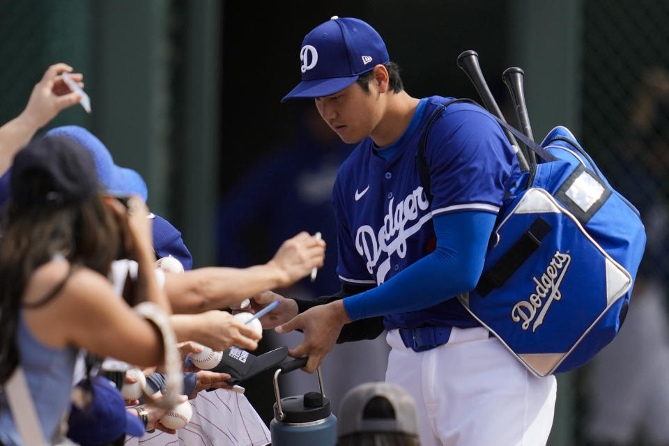 Los Angeles Dodgers designated hitter Shohei Ohtani signs autographs for fans before a spring training baseball game against the Chicago White Sox in Phoenix, Tuesday, Feb. 27, 2024. (AP Photo/Ashley Landis)