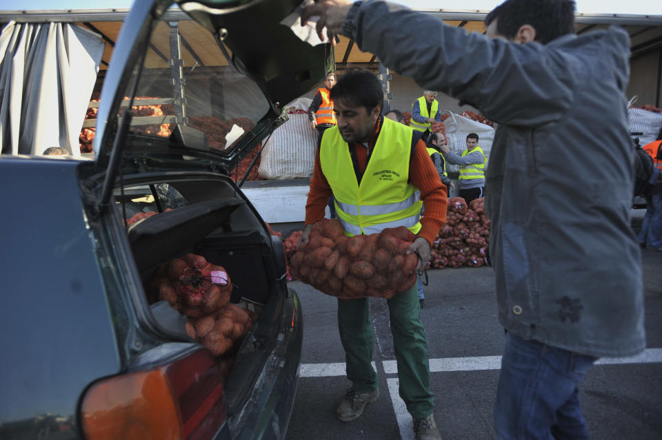 A farmer loads a car with sacks of potatoes sold at an extreme low price in the northern Greek town of Katerini, Greece on Saturday, Feb. 25 2012. Farmers in northern Greece have joined forces with local residents to provide cheap produce to people whose family budgets have been slashed by the financial crisis, and also to help producers who say they are being squeezed by middlemen. Hundreds of families turned up Saturday in this northern Greek town to buy potatoes at massively reduced prices, sold directly by producers at cost price. (AP Photo/Nicolas Giakoumidis)