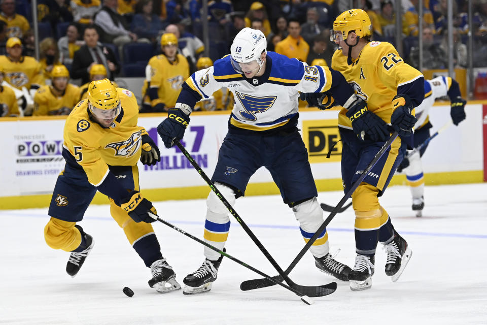 St. Louis Blues right wing Alexey Toropchenko (13) vies for the puck with Nashville Predators' Kevin Gravel (5) and Tyson Barrie (22) during the first period of an NHL hockey game, Saturday, April 1, 2023, in Nashville, Tenn. (AP Photo/Mark Zaleski)