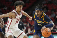 Kansas City guard RayQuawndis Mitchell drives past Oklahoma guard Milos Uzan (12) in the first half of an NCAA college basketball game, Tuesday, Dec. 6, 2022, in Norman, Okla. (AP Photo/Sue Ogrocki)