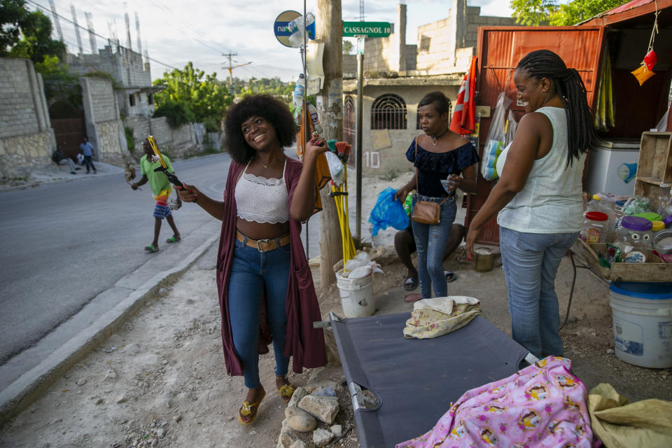 Semi Kaefra Alisha Fermond, una mujer transexual, sonríe tras recibir un caramelo de vendedores callejeros mientras camina hacia el centro Kay Trans Haití para celebrar su 24 cumpleaños, en Puerto Príncipe, Haití, el 7 de agosto de 2020. Los prejuicios y la discriminación contra las personas transexuales son habituales en Haití, pero al menos una organización les ofrece un refugio en el que pueden sentirse bienvenidas y aceptadas. (AP Foto/Dieu Nalio Chery)