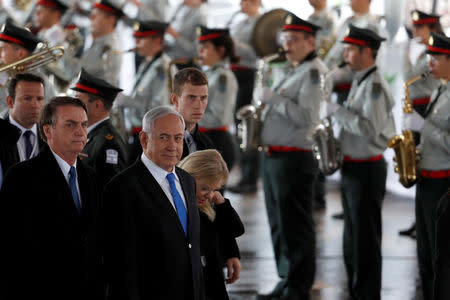 Brazilian President Jair Bolsonaro stands next to Israeli Prime Minister Benjamin Netanyahu and his wife Sara, as the Israeli military band perform during a welcoming ceremony upon his arrival in Israel, at Ben Gurion International airport in Lod, near Tel Aviv, Israel March 31, 2019. REUTERS/Ronen Zvulun