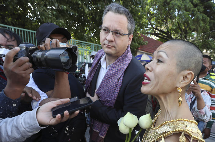 Theary Seng, right, a Cambodian-American lawyer, dressed an Apsara dancer, speaks with media with Jared Genser, center, former law school classmate and friend, as she arrives to continue her trial in the municipal court in Phnom Penh, Cambodia, Tuesday, Dec. 7, 2021. Seng and over 40 other defendants charged with treason for taking part in nonviolent political activities were summoned back to court Tuesday to continue their trial that had been suspended since November 2020 due to the coronavirus. (AP Photo/Heng Sinith)