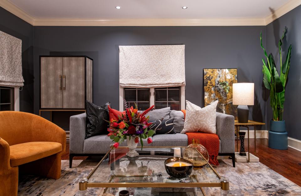 The den features a sofa from Moe’s and a rug from Jaipur Living. The pillows throughout are from Ngala Trading Co. and Kelly Wearstler, and the media console is a Noir design. The roman shades are Fabricut.