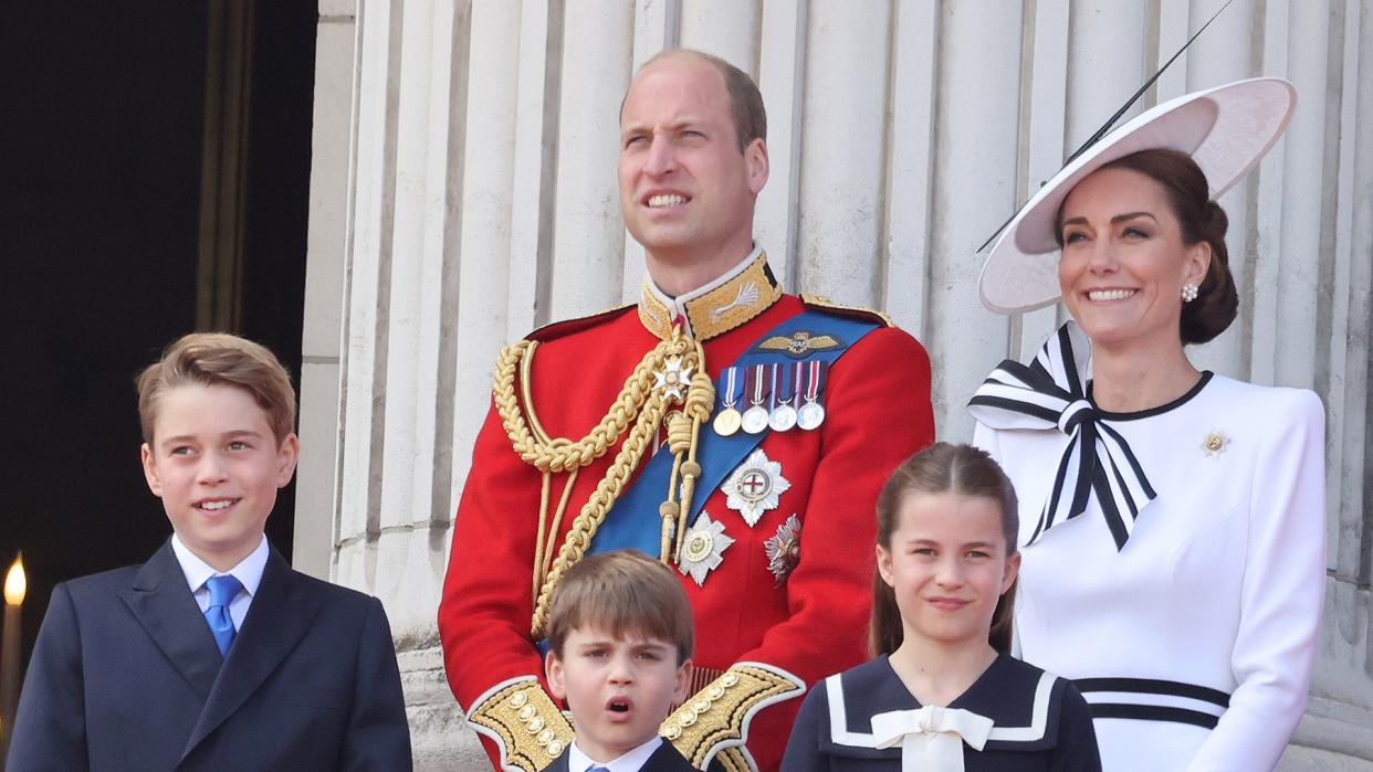 Prince George, Prince Louis, Princess Charlotte standing in front of Prince William and Princess Kate