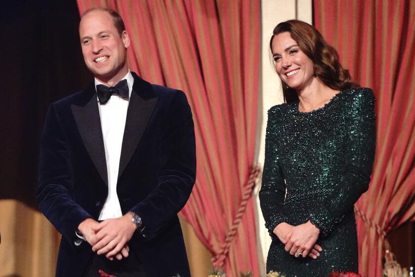 Britain's Prince William and Kate in formal attire smile while standing in front a curtain