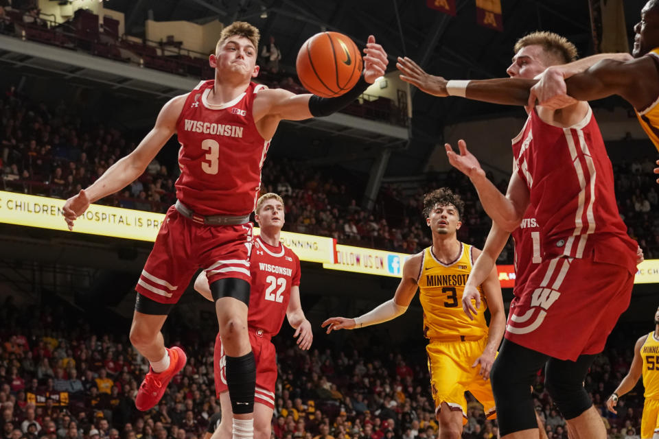 Wisconsin guard Connor Essegian (3) grabs a rebound in front of forward Steven Crowl (22) Minnesota forward Dawson Garcia (3) and Wisconsin forward Tyler Wahl, right, during the first half of an NCAA college basketball game on Sunday, March 5, 2023, in Minneapolis. (AP Photo/Craig Lassig)