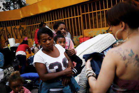 A homeless family (L) that was living in a building that caught fire and collapsed in the center of Sao Paulo picks up clothes donated by well-wishers, next to a church at Largo do Painsandu Square in Sao Paulo, Brazil May 1, 2018. REUTERS/Nacho Doce