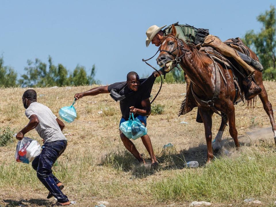 A US Border Patrol agent on horseback grabbing a Haitian migrant.