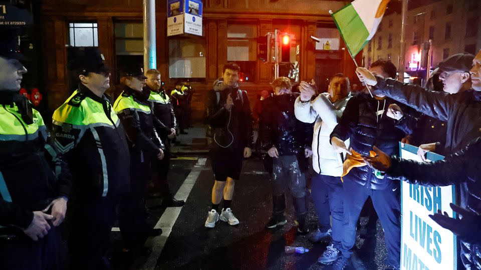 People stand in front of riot police, near the scene of a suspected stabbing that left few children injured in Dublin, Ireland. - Clodagh Kilcoyne/Reuters