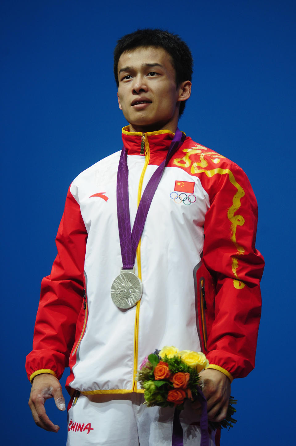 LONDON, ENGLAND - JULY 29: Jingbiao Wu of China celebrates with the silver medal on the podium after the Men's 56kg Weightlifting on Day 2 of the London 2012 Olympic Games at ExCeL on July 29, 2012 in London, England. (Photo by Laurence Griffiths/Getty Images)