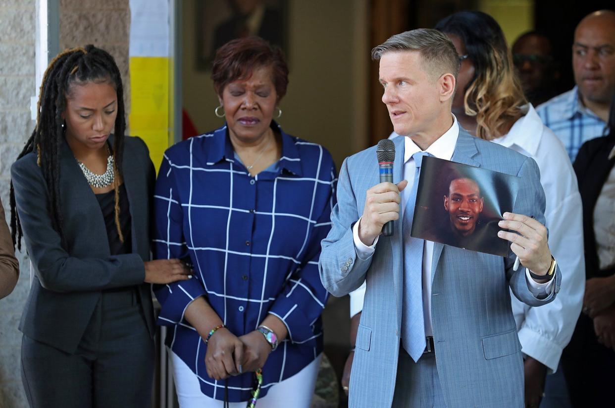 Attorney Bobby DiCello, right, holds up a photograph of Jayland Walker as attorney Paige White, left, comforts Jayland's mother Pamela Walker Thursday.