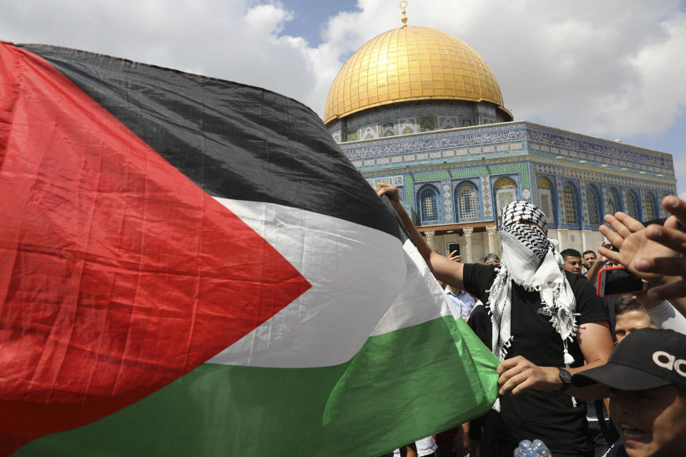 Protesters hold a Palestinian flag during a protest celebrating the six Palestinian prisoners who recently tunneled out of the Gilboa Prison, after Friday prayers at the Dome of the Rock Mosque in the Al Aqsa Mosque compound in in the Old City of Jerusalem, Friday, Sept. 10, 2021. (AP Photo/Mahmoud Illean)