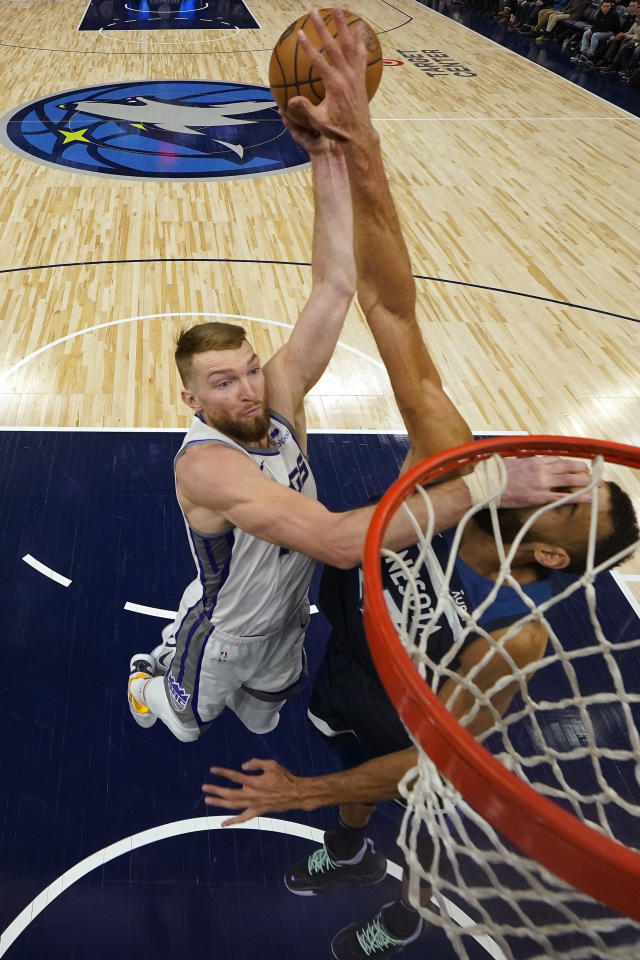 Sacramento Kings forward Domantas Sabonis, left, goes up to shoot while defended by Minnesota Timberwolves center Rudy Gobert, right, during the first half of an NBA basketball game, Monday, Jan. 30, 2023, in Minneapolis. (AP Photo/Abbie Parr)