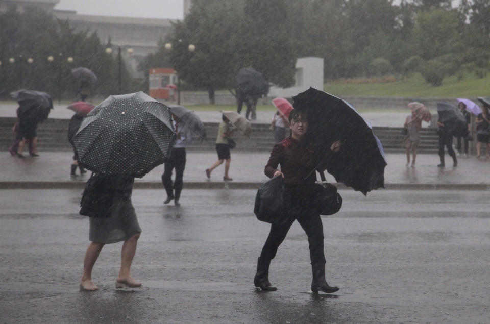 Pedestrians shield themselves from wind and rain brought by Typhoon Lingling Saturday, Sept. 7, 2019, in Pyongyang, North Korea. The typhoon passed along South Korea’s coast has toppled trees, grounded planes and caused at least two deaths before making landfall in North Korea. (AP Photo/Jon Chol Jin)