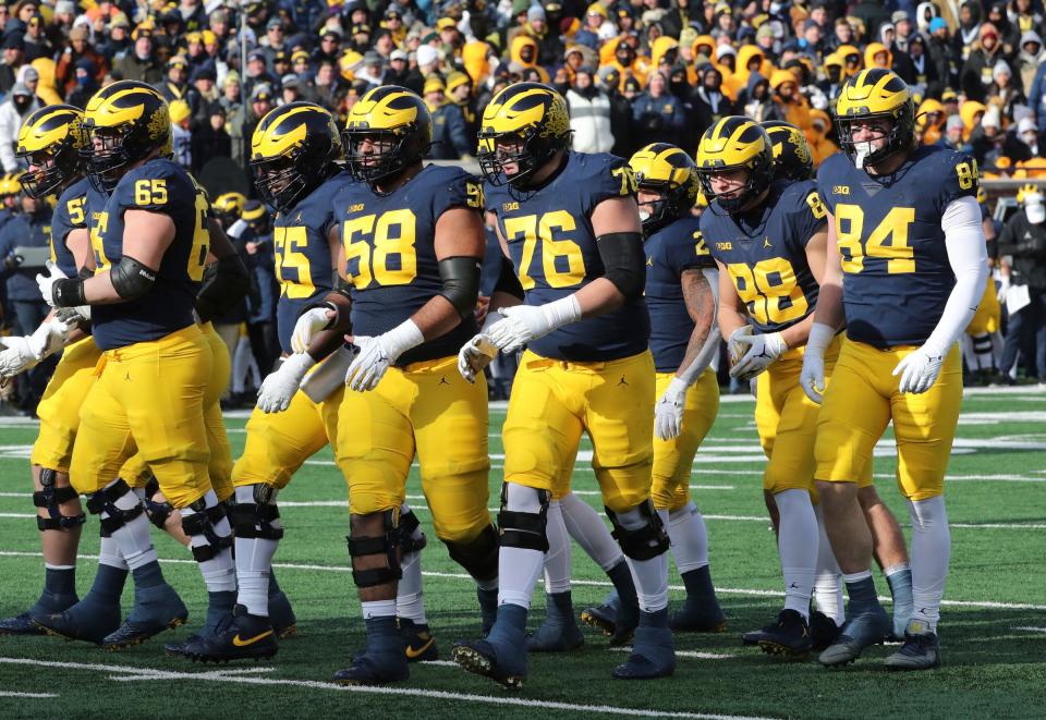 The Michigan Wolverines offensive line, including Zak Zinter (65), Olusegun Oluwatimi (55), Giovanni El-Hadi (58) and Ryan Hayes (76), and tight ends Matthew Hibner (88) and Joel Honigford, get set against the Illinois Fighting Illini at Michigan Stadium on Nov. 19, 2022.