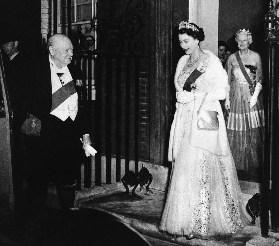 British Prime Minister Winston Churchill bids farewell to Queen Elizabeth II at the end of a dinner he hosted at No. 10 Downing Street in London on April 4, 1955. Lady Churchill stands in the doorway as she follows the queen. (AP)