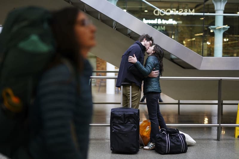 A couple kisses as passengers wait for trains at London's St Pancras Station as the getaway continues for the Easter weekend. Jordan Pettitt/PA Wire/dpa