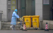 Staff move bio-waste containers past the entrance of the Wuhan Medical Treatment Center, where some infected with a new virus are being treated, in Wuhan, China, Wednesday, Jan. 22, 2020. The number of cases of a new coronavirus from Wuhan has risen over 400 in China Chinese health authorities said Wednesday. (AP Photo/Dake Kang)