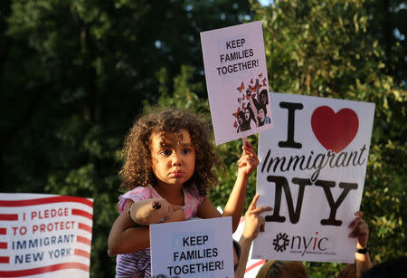 A girl sitting on the shoulders of her father holds a sign reading "Keep Families Together" at a protest against U.S. President Donald Trump's proposed end of the DACA program that protects immigrant children from deportation in New York City, U.S., August 30, 2017. REUTERS/Joe Penney/Files