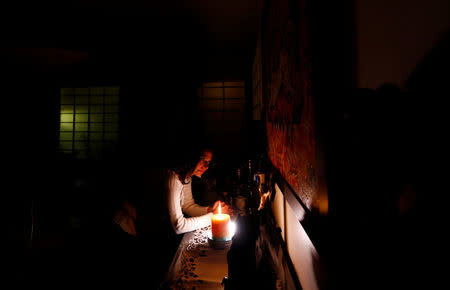 Maha Ragaay prays and lights a candle in front of a wooden figure of Jesus on a cross in her home at the Cairo suburb of Maadi, Egypt, April 14, 2017. REUTERS/Amr Abdallah Dalsh