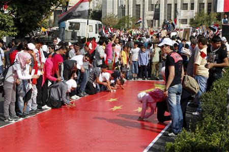 Supporters of Syrian President Bashar al-Assad's sign a Chinese flag during a rally at al-Sabaa Bahrat square in Damascus October 12, 2011. REUTERS/ Khaled al-Hariri