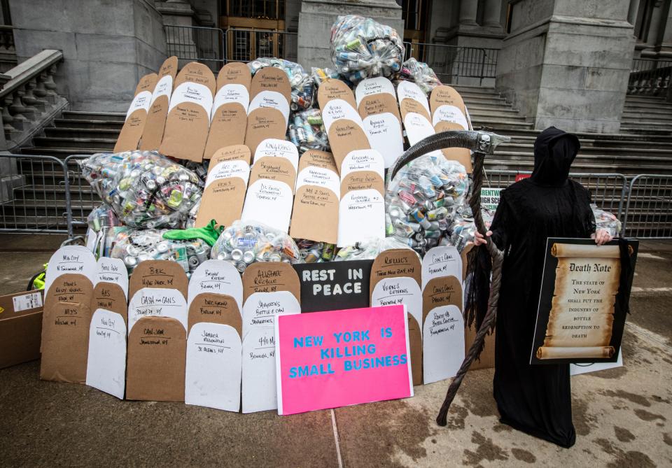 Jade Eddy, owner of MT Returnables in Queensbury, N.Y. was dressed as the grim reaper as she stood by cardboard tombstones with the names of recycling centers that have gone out of business outside the New York State Capitol in Albany May 6, 2024. Eddy was among dozens of bottle collectors and others from the redemption industry to call for the passage of bills that would modernize the New York State Bottle Bill. Among the changes in the law that bottle collectors, owners of redemption centers, and environmental groups want to see is the deposit fee raised to 10 cents from the present five cents per bottle. They also want to see an increase in the number of containers that are eligible for deposit.