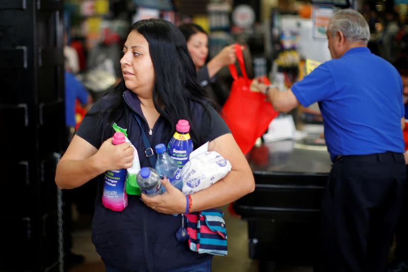 A woman carries loose items as she leaves a supermarket which no longer provides plastic bags for customers to carry products, in Mexico City