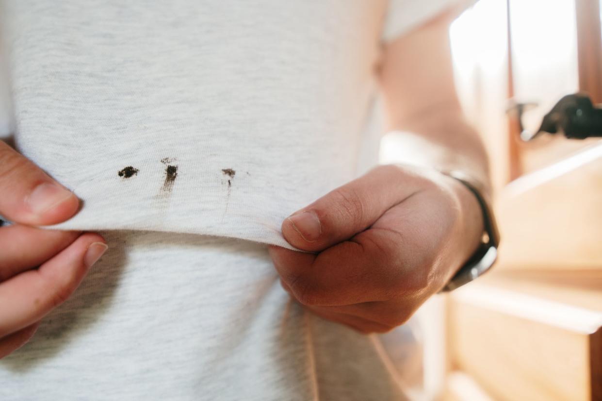 Two hands showing stains on a T-shirt