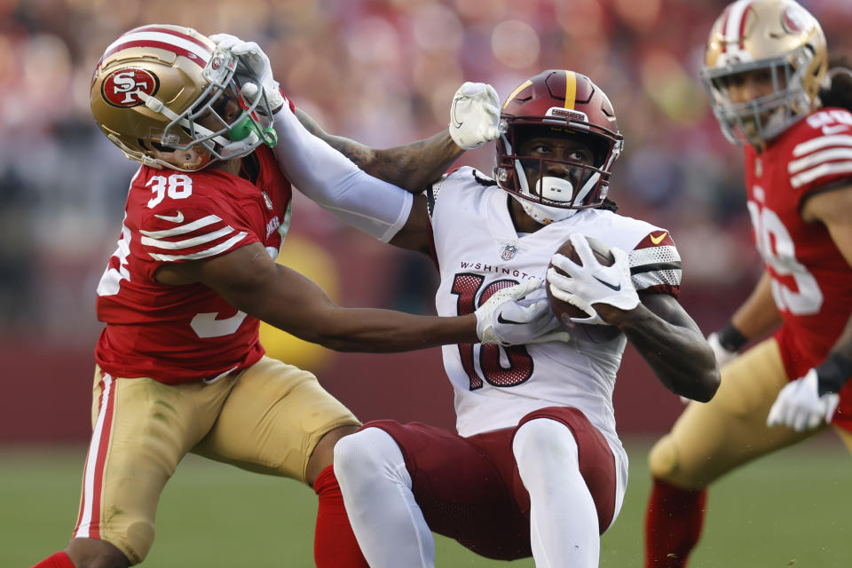 Washington Commanders wide receiver Curtis Samuel, center, tries to break free from San Francisco 49ers cornerback Deommodore Lenoir as he rushes the ball in the second half of an NFL football game, Saturday, Dec. 24, 2022, in Santa Clara, Calif. (AP Photo/Jed Jacobsohn)