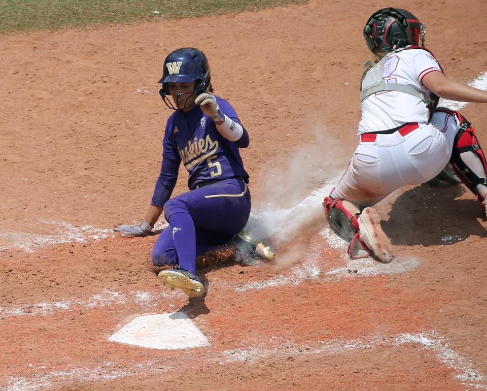 Washington's Avery Hobson (5) slides past Utah's Kendall Lundberg (32) to score a run in the fourth inning of a softball game between Utah and Washington in the Women's College World Series at USA Softball Hall of Fame Stadium in Oklahoma City, Friday, June 2, 2023. Washington won 4-1.