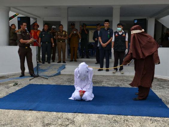 The latest recruit of the eight-member flogging team whips an unmarried woman who was caught in a hotel room with a man (CHAIDEER MAHYUDDIN/AFP via Getty Images)