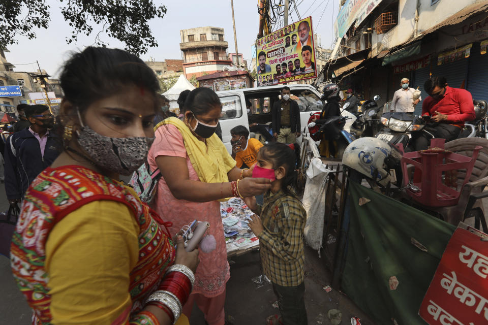 A woman puts on a face mask on her daughter at a market place in New Delhi, India, Thursday, Nov. 19, 2020. India’s total number of coronavirus cases since the pandemic began has crossed 9 million. Nevertheless the country’s new daily cases have seen a steady decline for weeks now and the total number of cases represents 0.6% of India’s 1.3 billion population. (AP Photo/Manish Swarup)