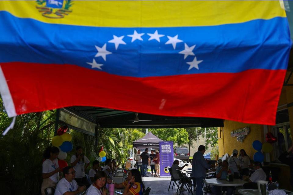 Miembros de la comunidad de exiliados venezolanos se reúnen a la sombra en el restaurante local Arepazo en Doral, Florida, el domingo 28 de julio de 2024, en Miami, Florida, para monitorear las elecciones en su tierra natal.